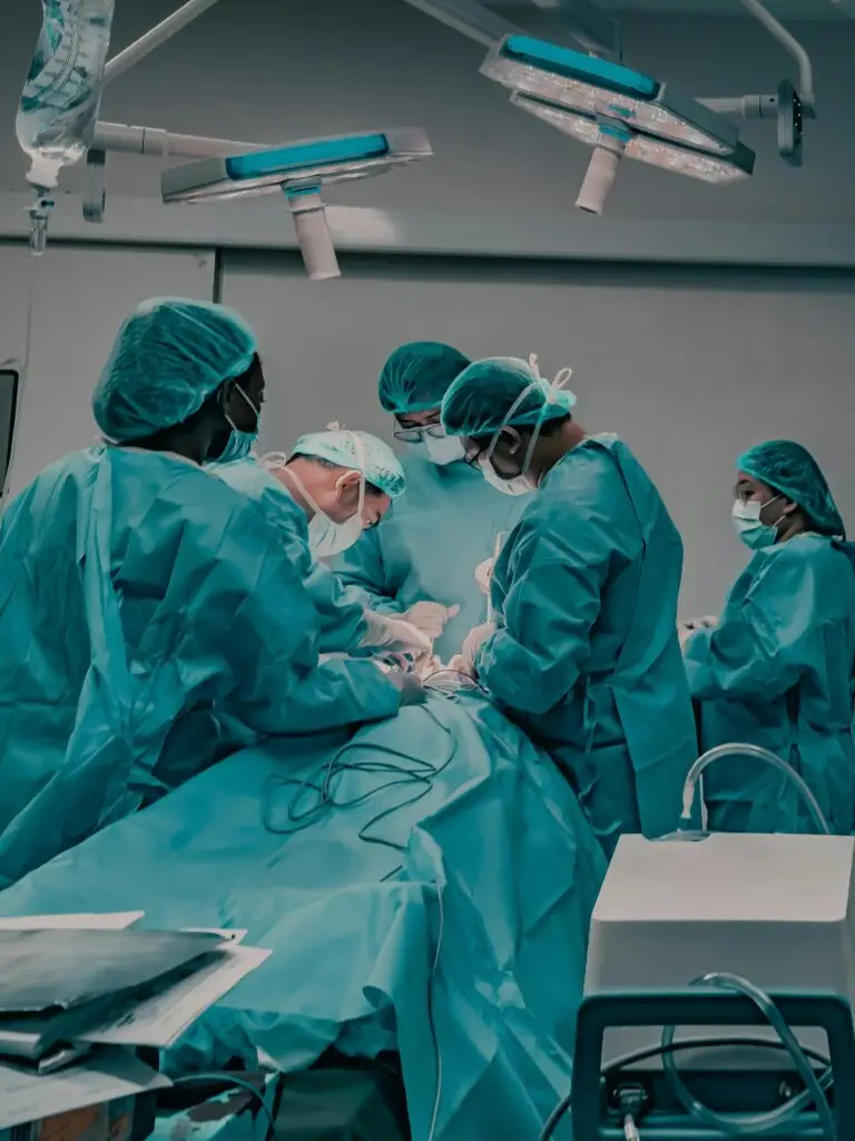 Medical professionals in scrubs conduct surgery in a hospital operating room.